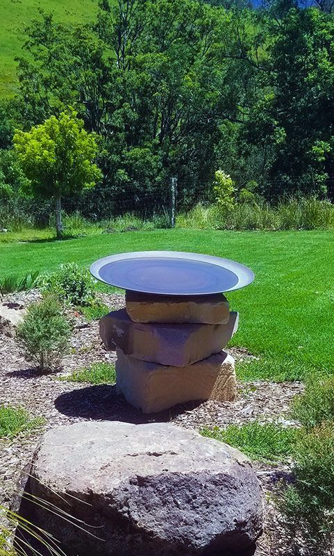 A Bird Bath Is Sitting On Top Of A Pile Of Rocks In A Garden — Full Circle Landscaping in Uki, NSW