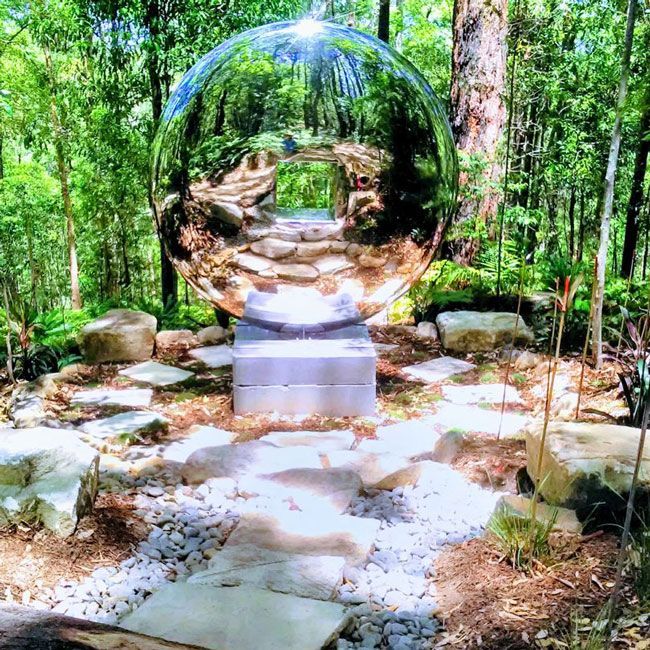 A Large Stainless Steel Sphere Is Sitting In The Middle Of A Forest — Full Circle Landscaping in Uki, NSW