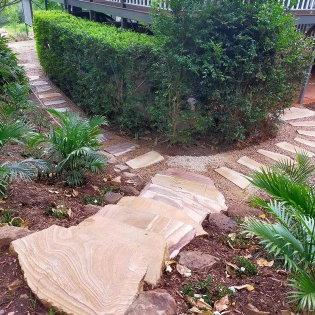 A Stone Walkway In A Garden Next To A House — Full Circle Landscaping in Uki, NSW