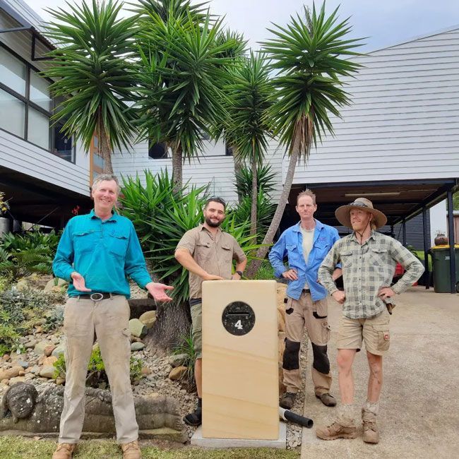 A Group Of Men Standing In Front Of A Stone With The Number 4 On It — Full Circle Landscaping in Uki, NSW