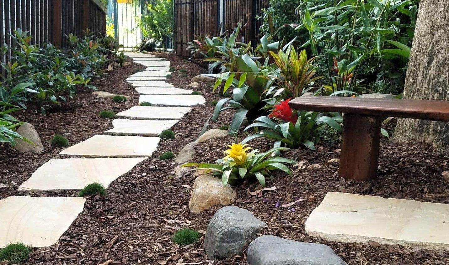 A Wooden Bench is Sitting on the Side of a Path in a Garden — Full Circle Landscaping in Uki, NSW
