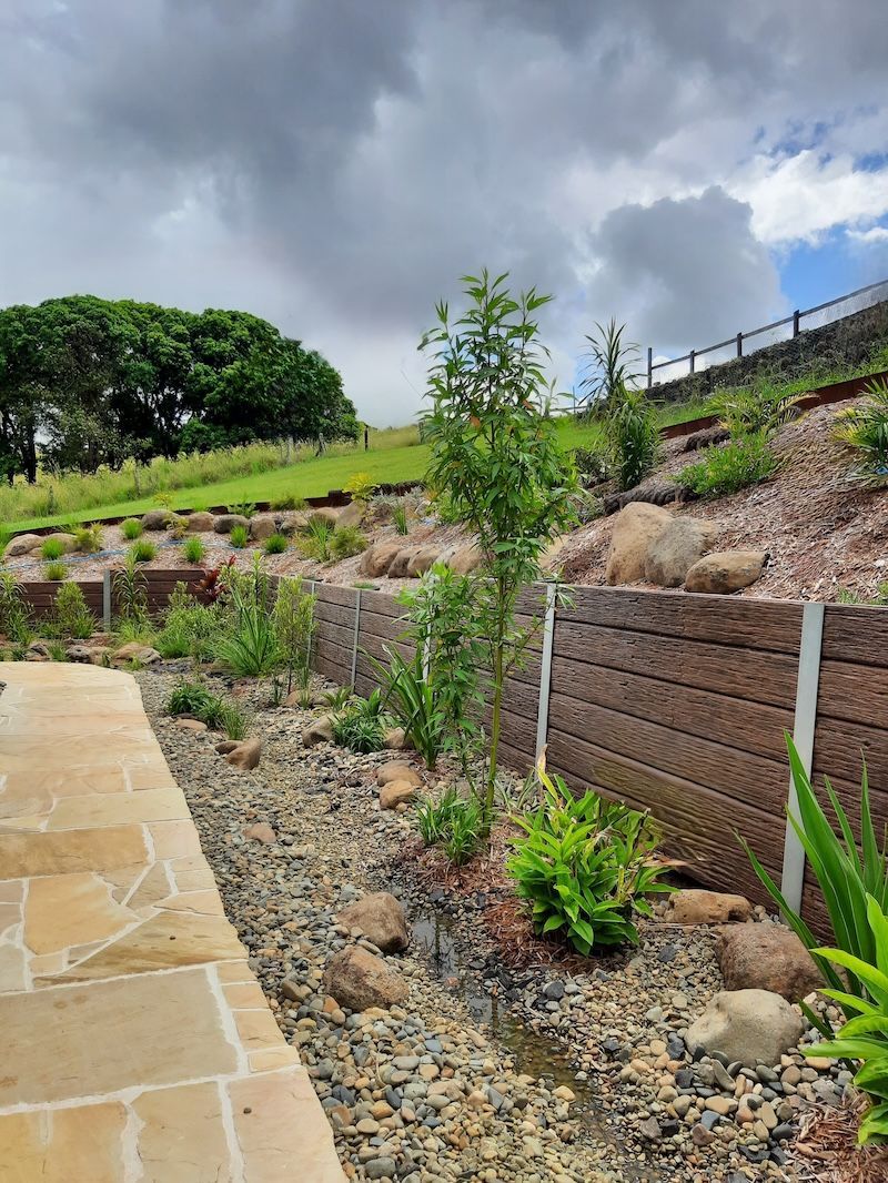 A Red Kubota Excavator Is Working On A Rocky Hillside — Full Circle Landscaping in Uki, NSW