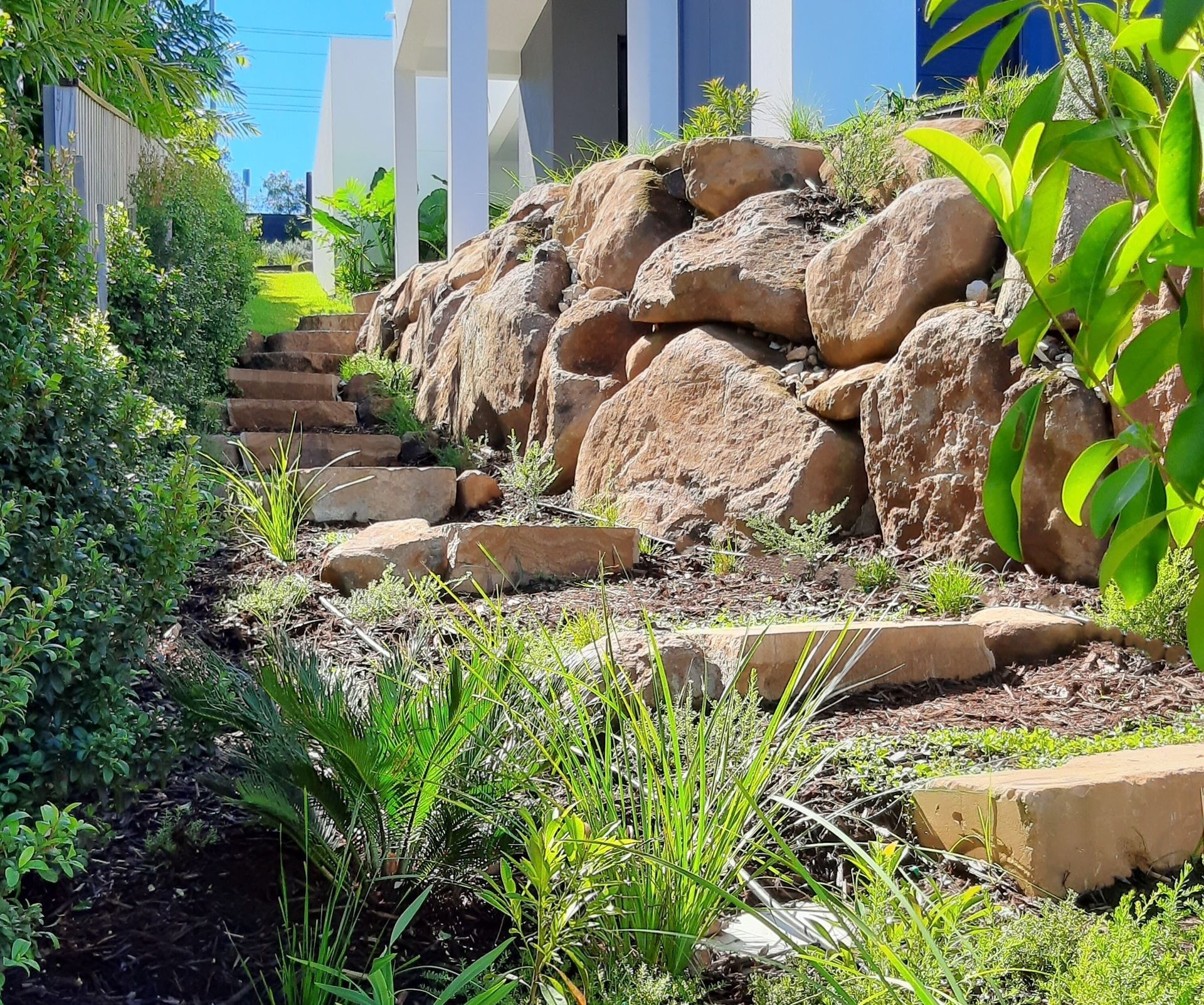 A Garden With Flowers And Plants In Front Of A House — Full Circle Landscaping in Uki, NSW