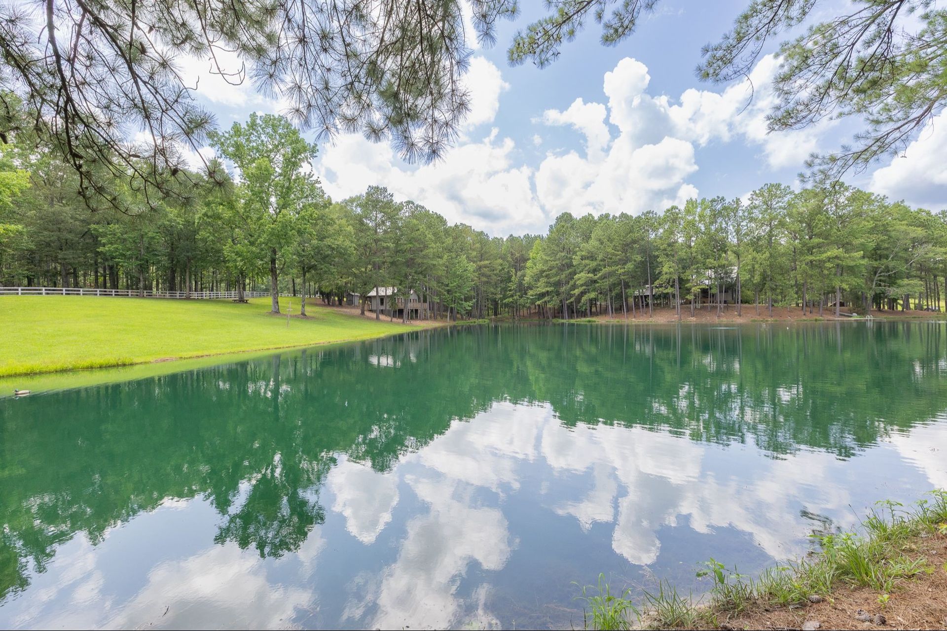 A lake with trees and clouds reflected in it