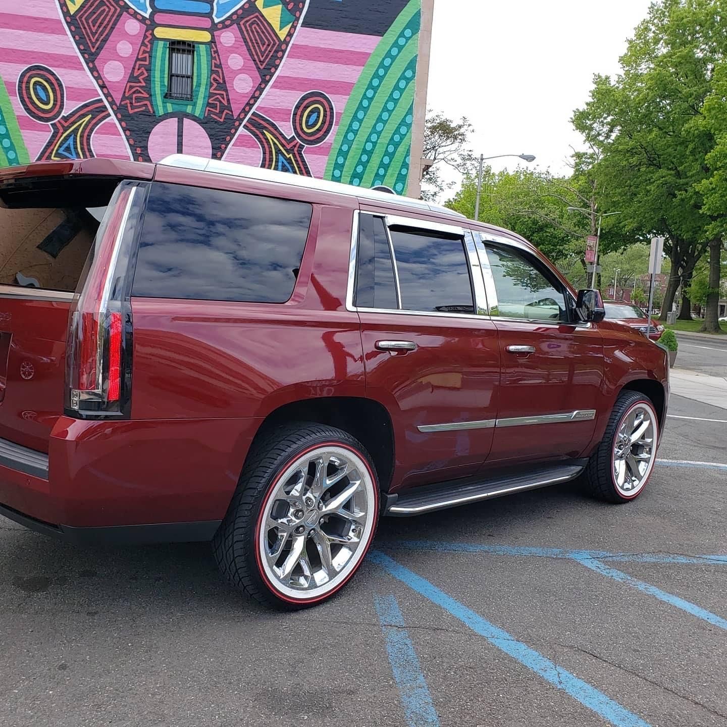 a red suv is parked in a parking lot in front of a mural .