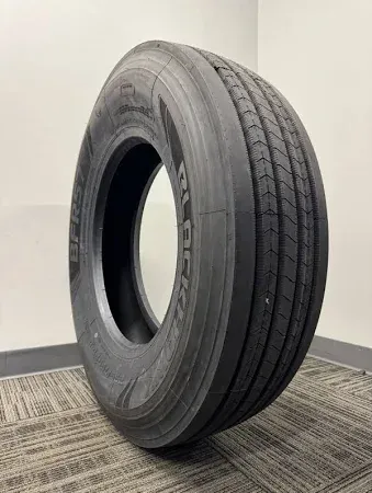 A large BlackHawk BFR57 Steer Tire is sitting on a carpeted floor in a room.