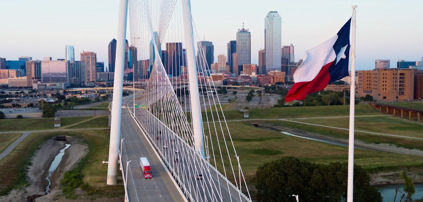 An aerial view of a bridge with a texas flag flying in the foreground.