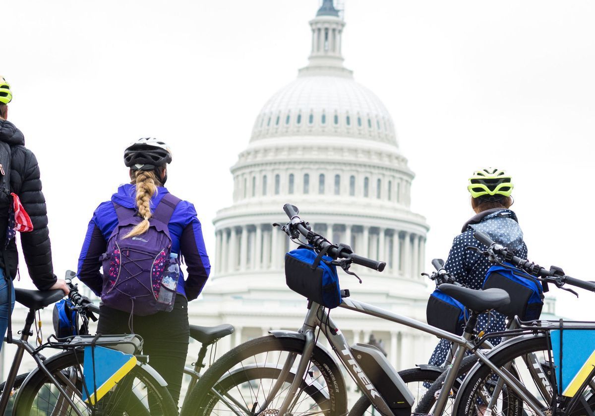 A group of people standing next to bicycles in front of the capitol building in Washington D. C.
