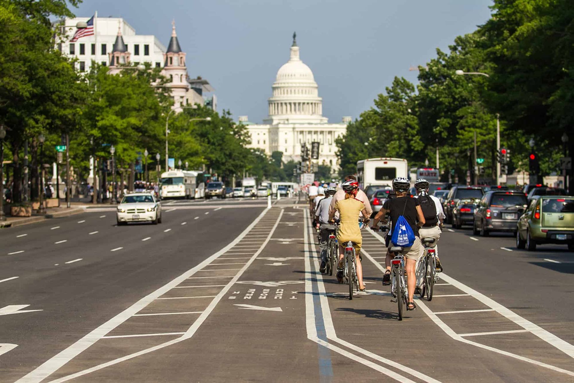 People riding e-bicycles down a street in front of the capitol building in D. C.