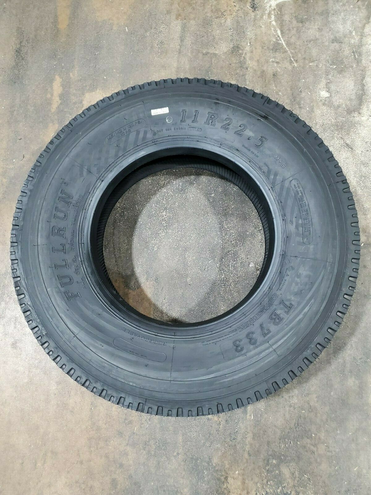 a black tire is sitting on a concrete surface .