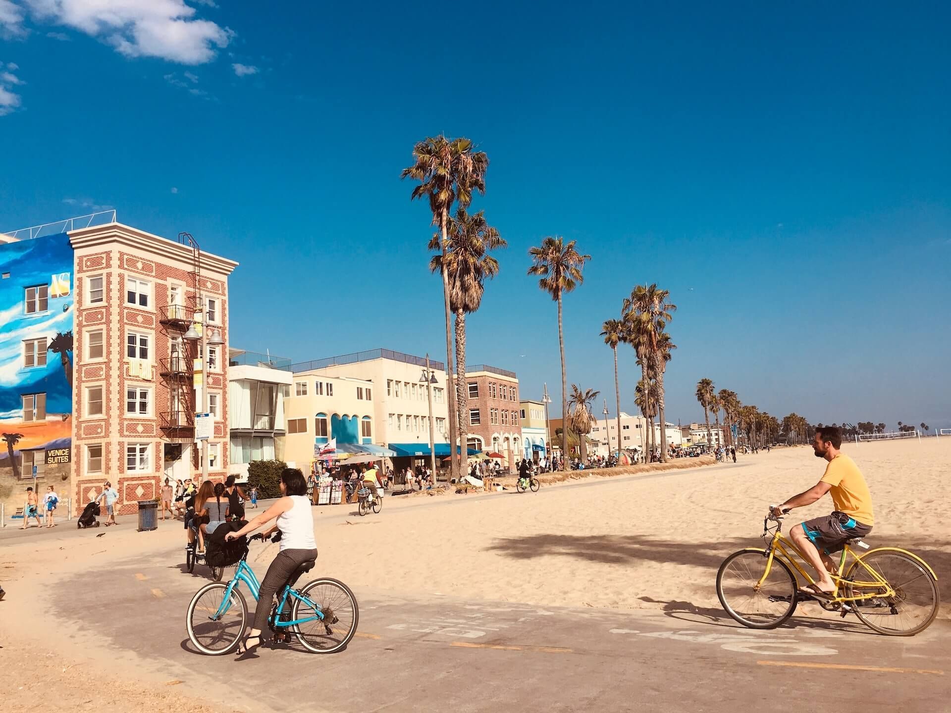 A man and a woman are riding bicycles on the Los Angeles beach.