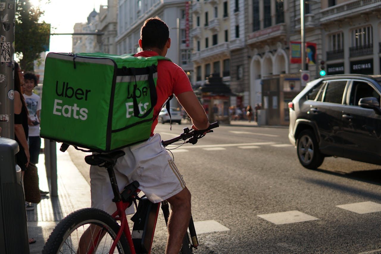 A man is riding a bike with an uber eats bag on his back IN NEW YORK