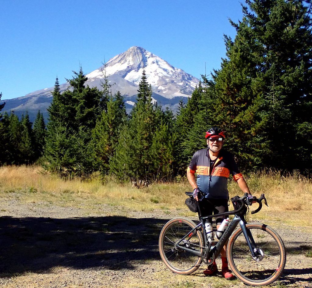 A man standing next to a bike with mt hood Oregon mountain in the background