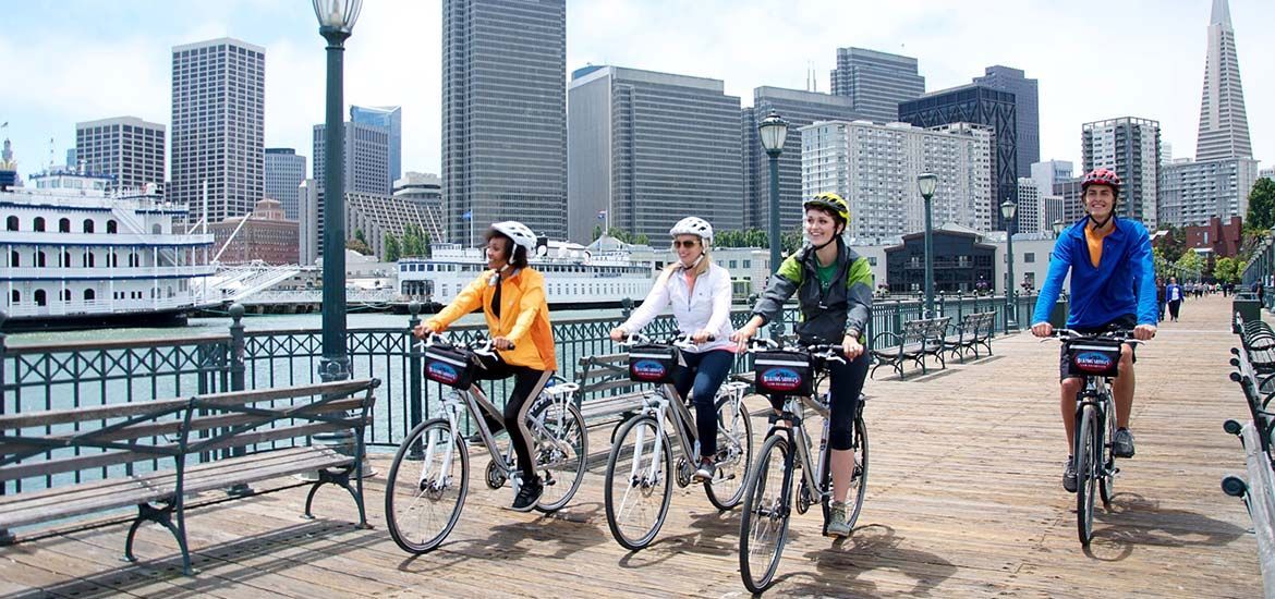 A group of people are riding bicycles on a San Francisco bridge.