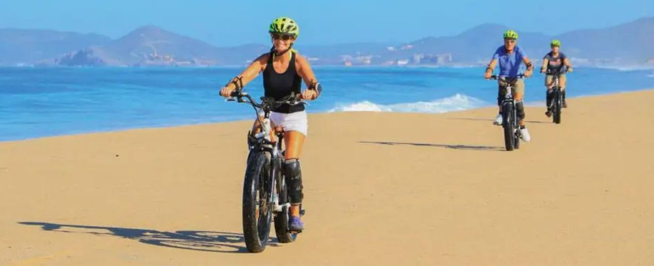 A group of people are riding bikes on the beach.
