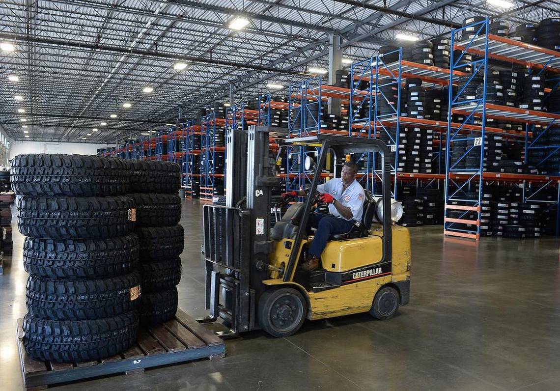 a man is driving a forklift in a warehouse filled with tires .