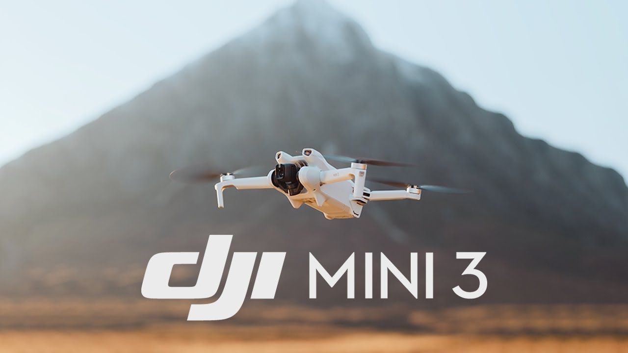 A dji mini 3 drone is flying in front of a mountain.