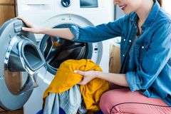 Donna che carica biancheria gialla in una lavatrice a carica frontale