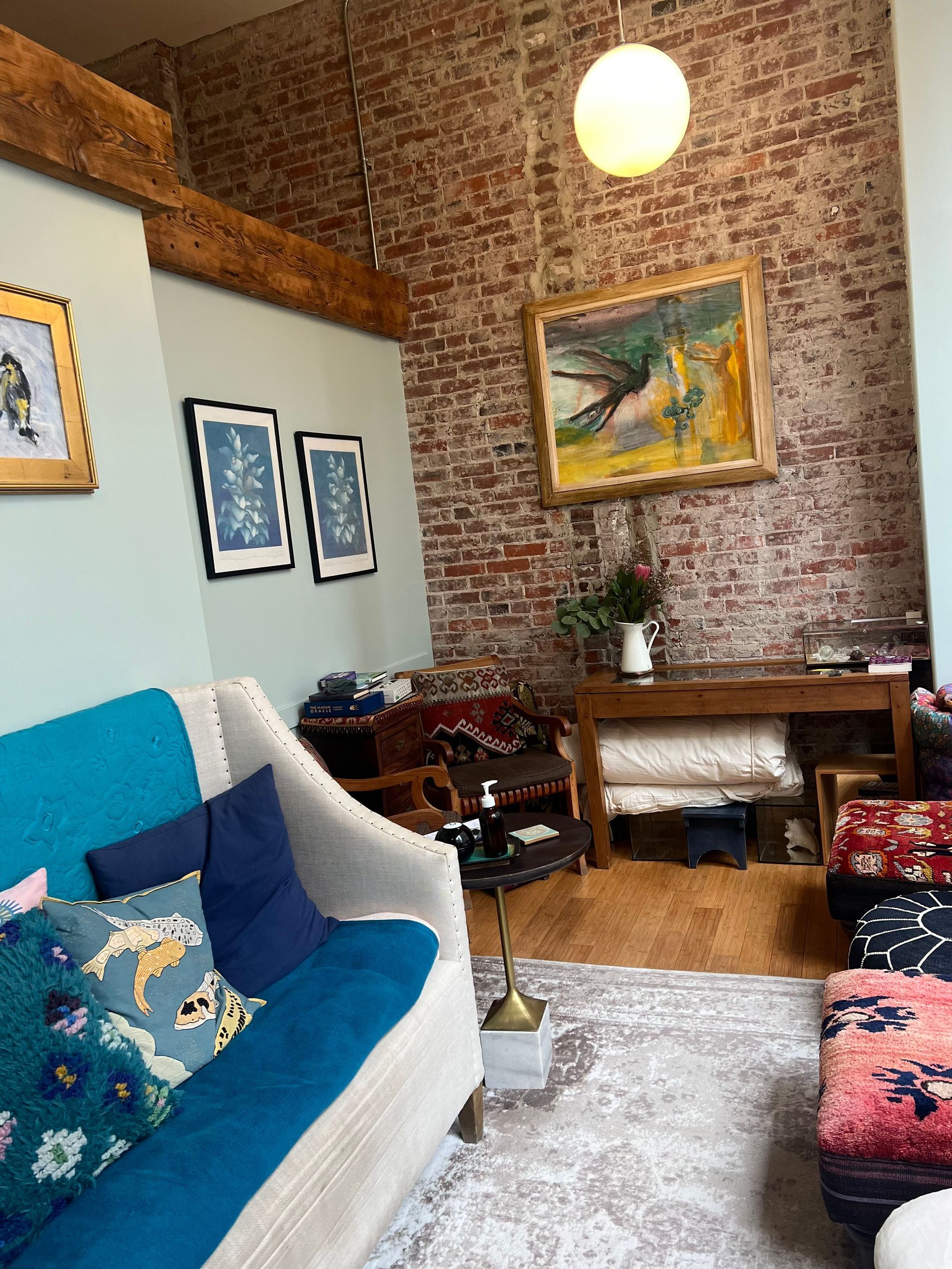 a living room with a blue couch and a brick wall