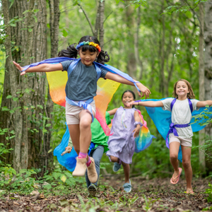 a group of children are playing in the woods with kites .