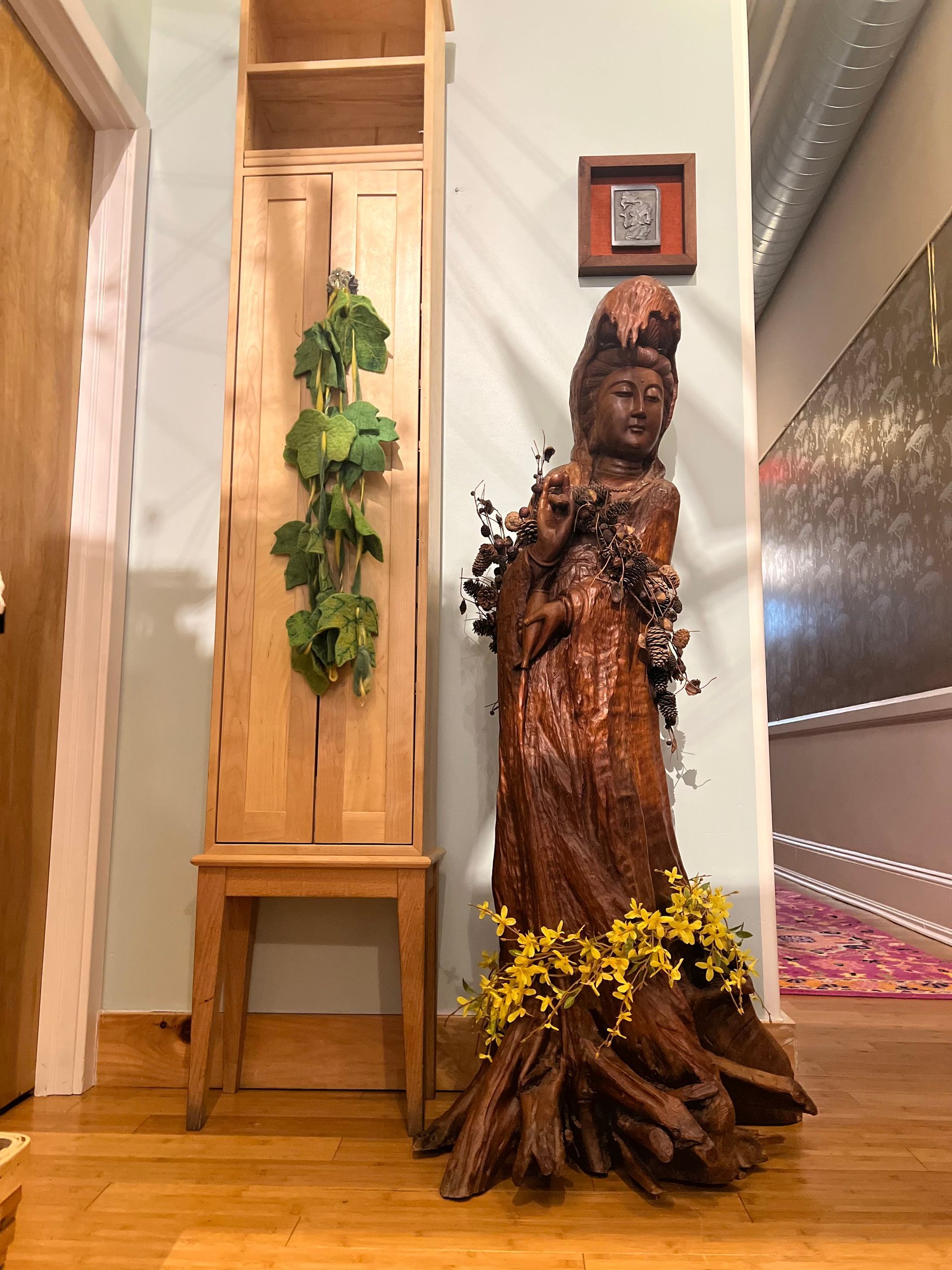 a wooden statue of a woman holding a baby in a hallway