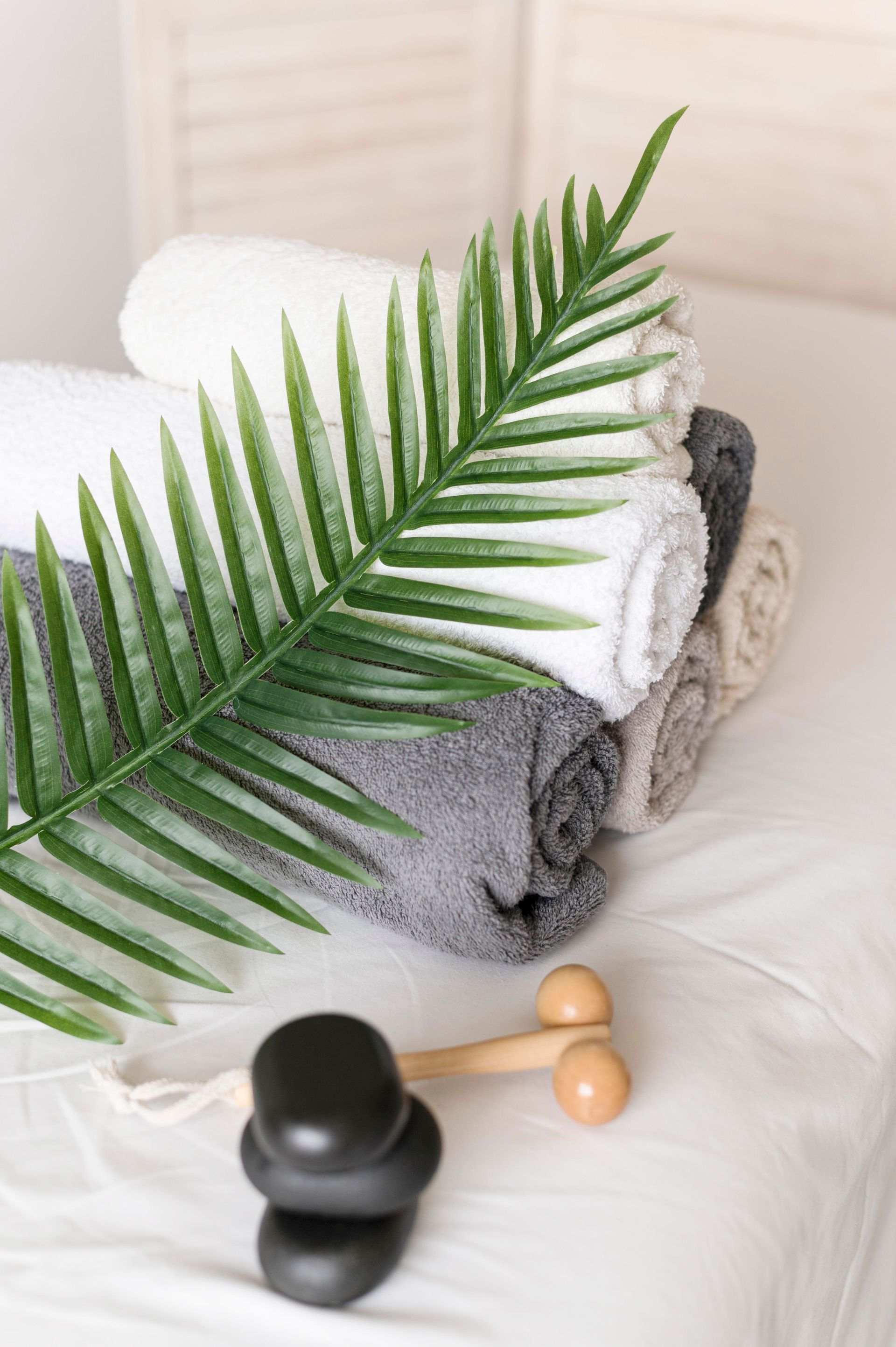 a stack of towels and a palm leaf on a table