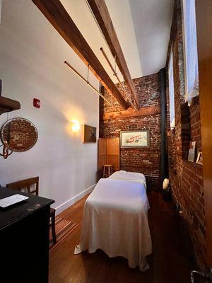 a massage table is sitting in a room with a brick wall .