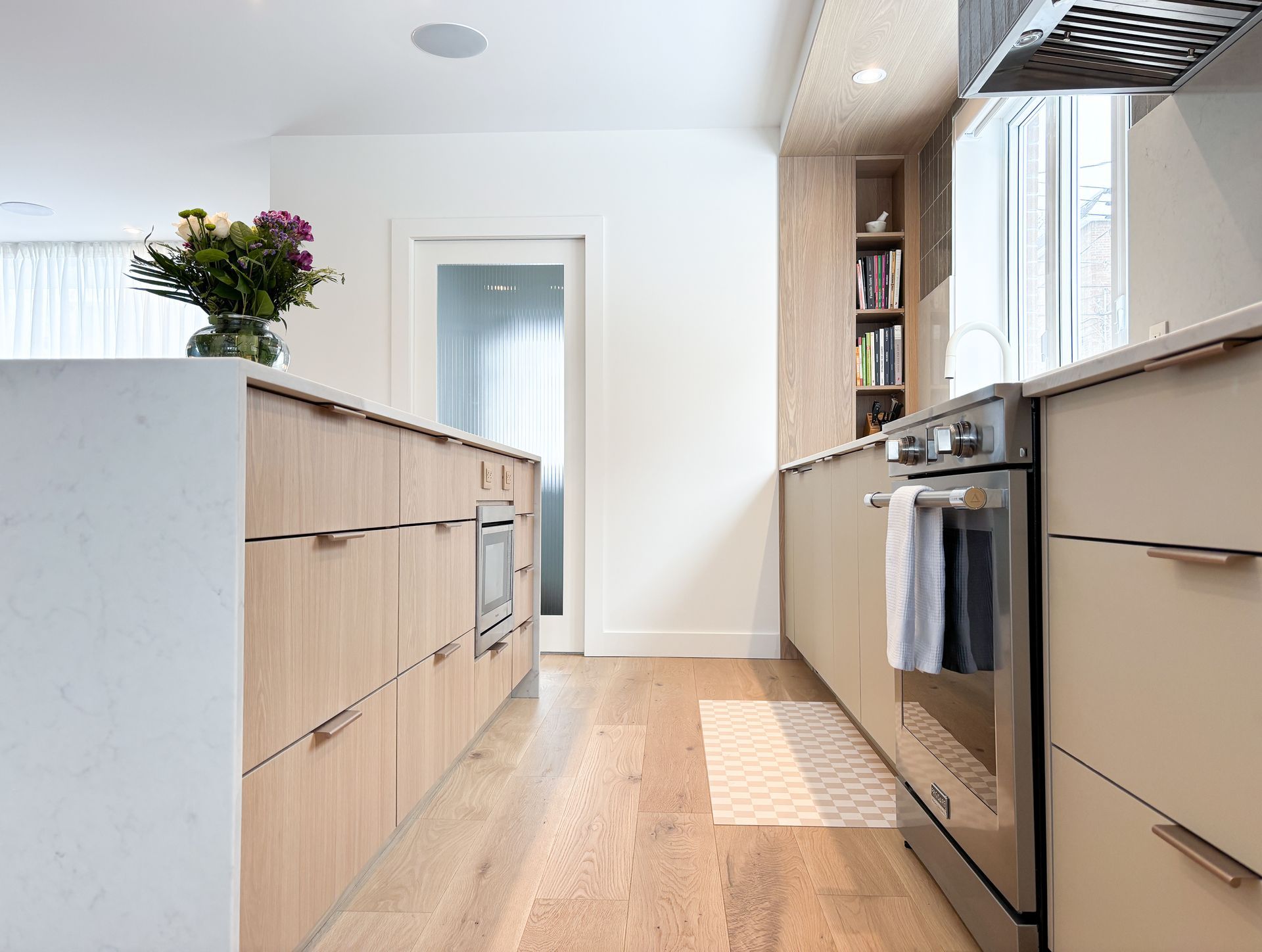 Cuisine moderne avec armoires en bois clair, électroménagers en acier inoxydable et îlot.