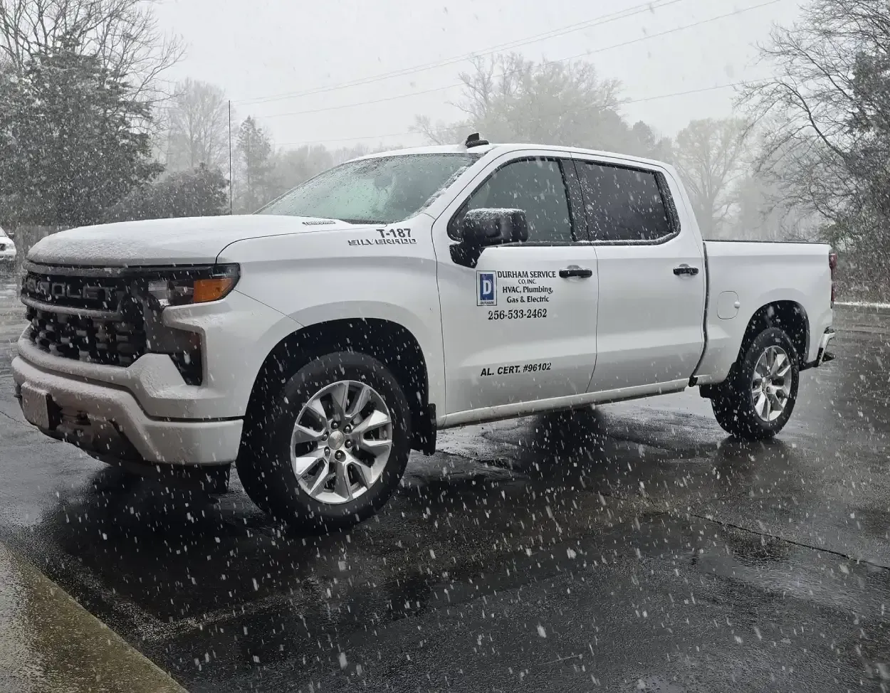 White pickup truck parked on a snowy road during a snowstorm