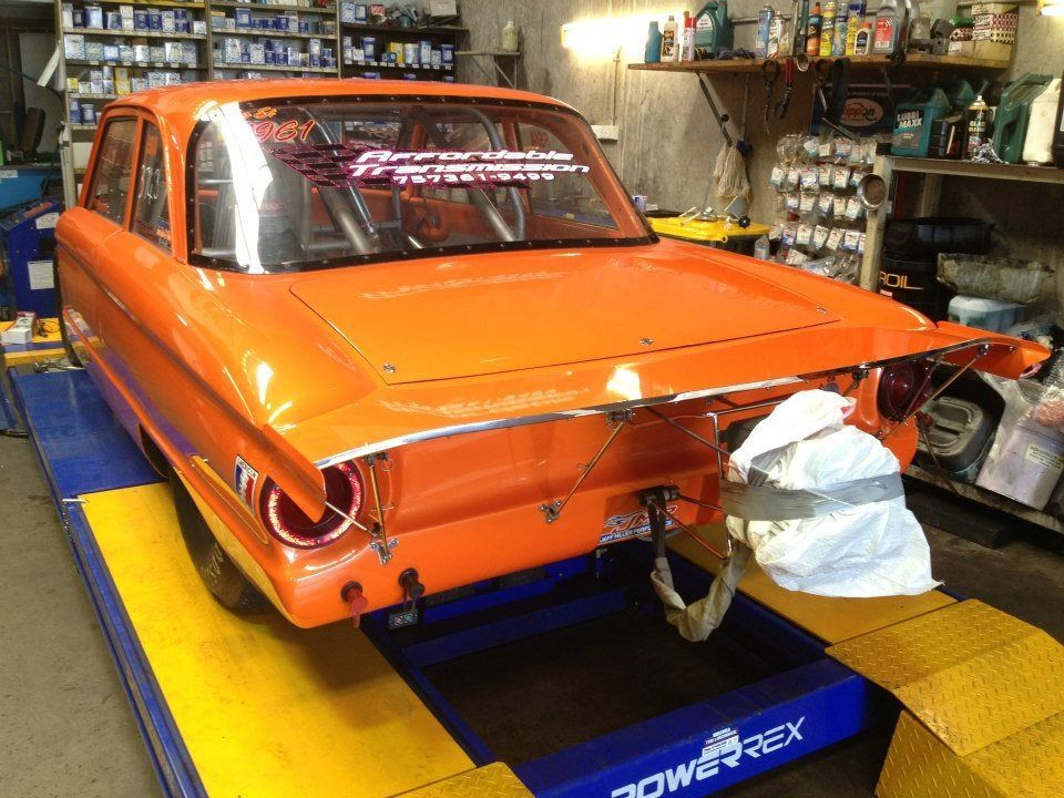 An Orange Car Is Sitting On A Lift In A Garage — Marcoola Tyre & Mechanical In Marcoola, QLD