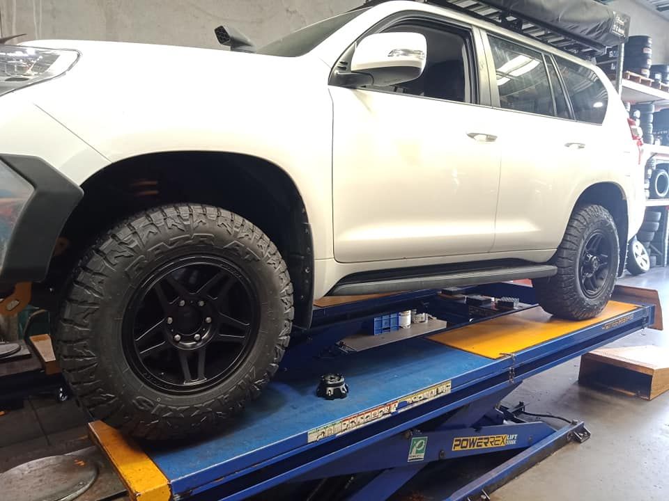 A White Suv Is Sitting On A Lift In A Garage — Marcoola Tyre & Mechanical In Marcoola, QLD