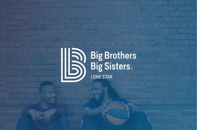 Two men are sitting in front of a brick wall holding a basketball.