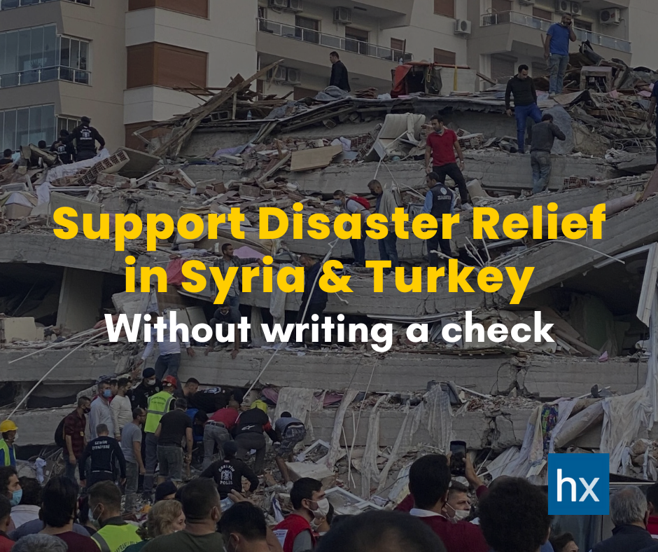 A group of people are standing in front of a building that has fallen down.