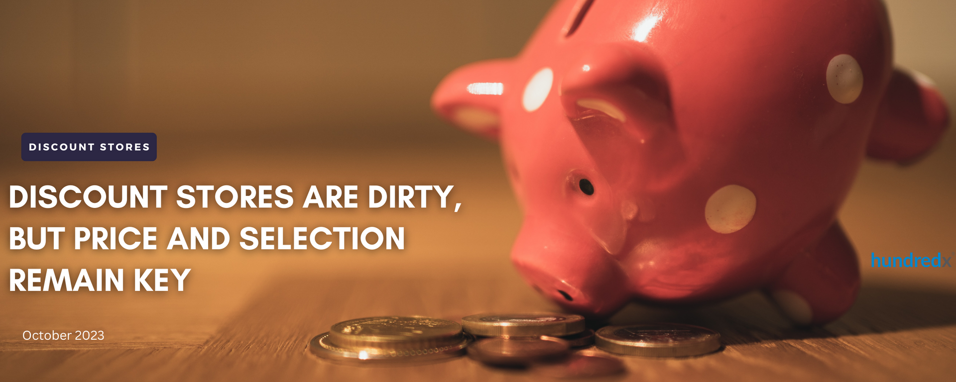 A pink piggy bank is sitting on a wooden table next to a pile of coins.