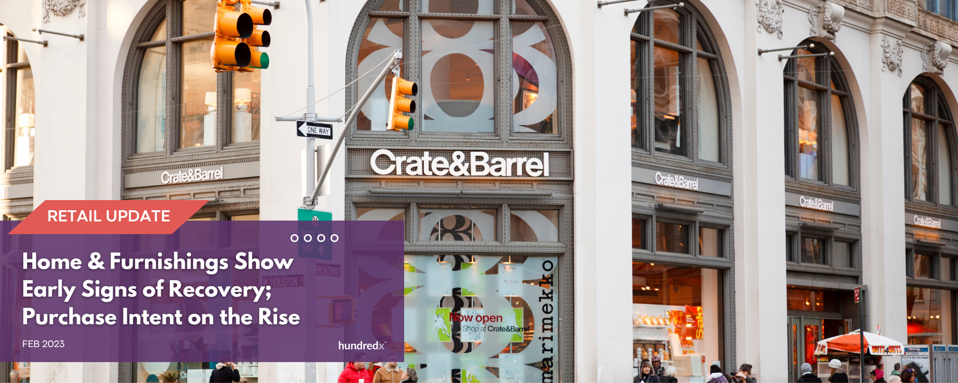 A group of people are walking down a street in front of a store called crate & barrel.