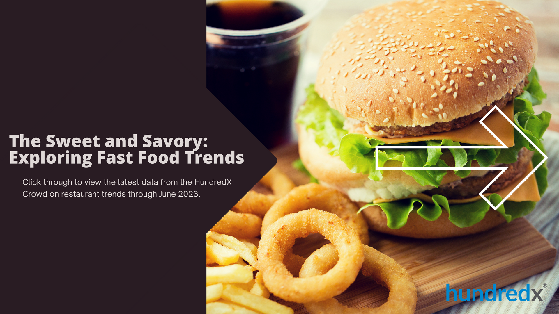 A hamburger and onion rings are on a cutting board next to a cup of soda.