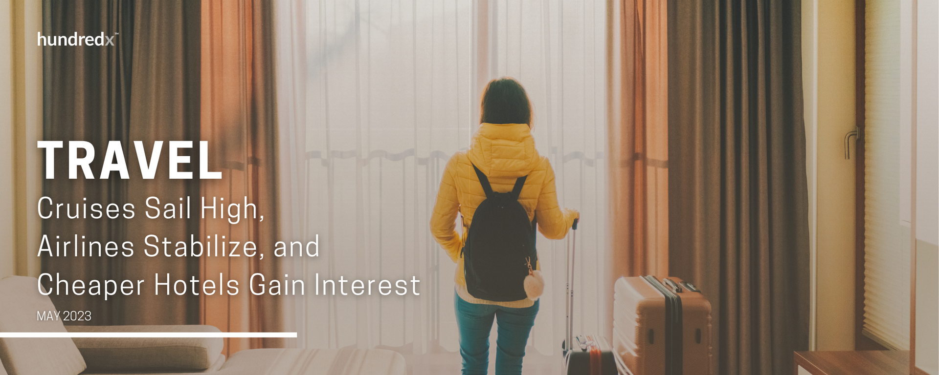 A woman is walking with a suitcase in a hotel room.