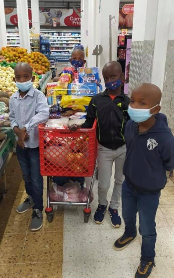 A group of children wearing face masks are standing in a grocery store.