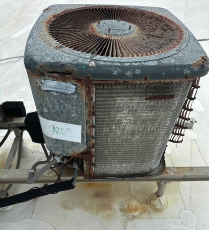 Rusty, old air conditioning unit on a metal stand, with a corroded exterior.