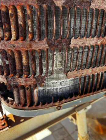 Heavily rusted air conditioner coil with damaged fins.