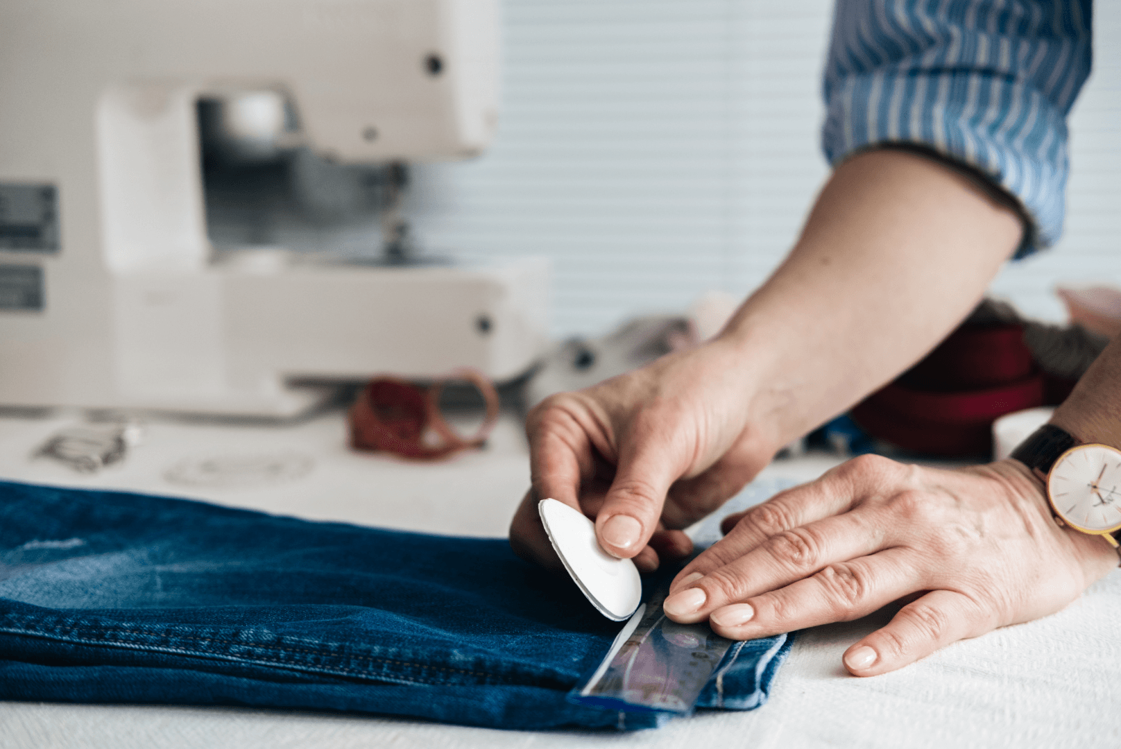 A person is cutting a pair of jeans with a ruler.