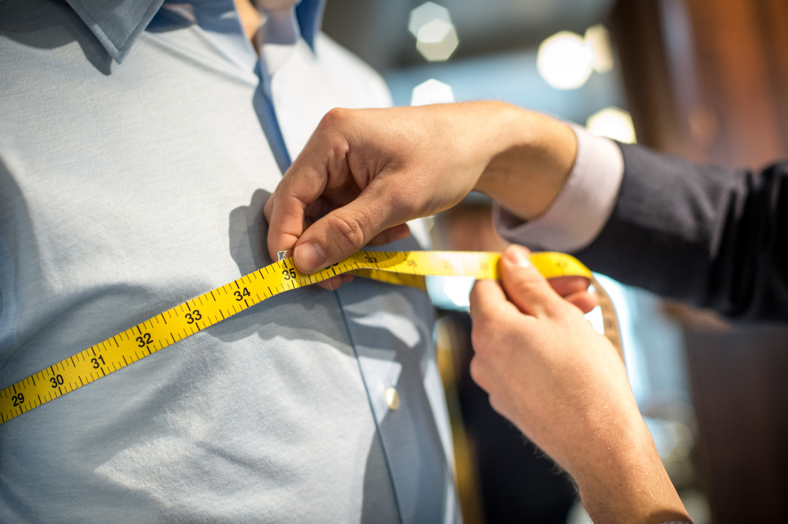 A man is being measured by a tailor with a tape measure.