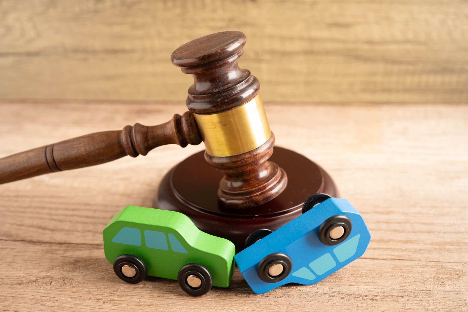 Judge gavel behind two wooden car models, symbolizing a car accident lawsuit and insurance. Judge gavel behind two wooden car models, symbolizing a car accident lawsuit and insurance.