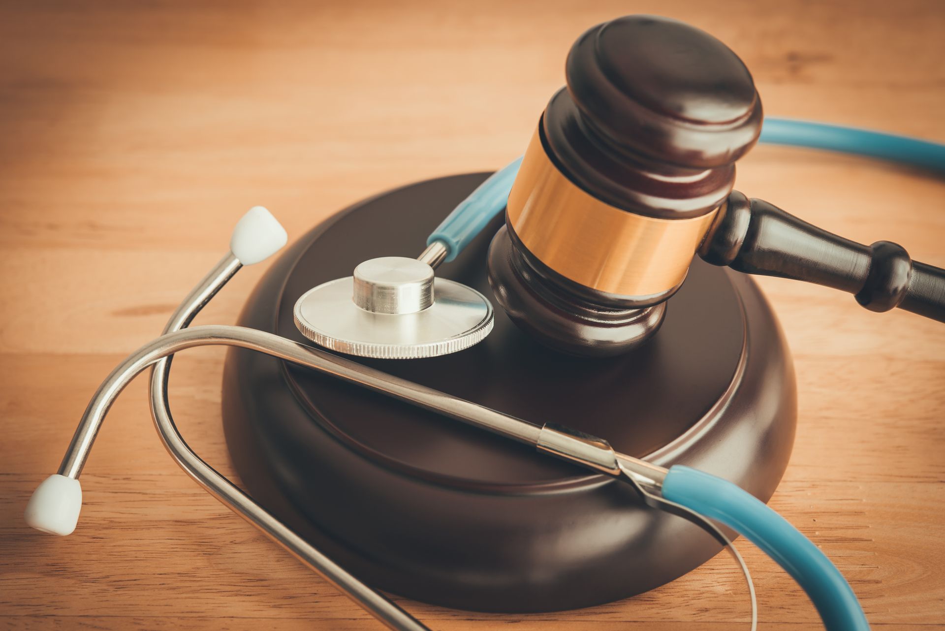 Judge gavel and a stethoscope on wooden table, symbolizing the work of a hospital malpractice attorney.