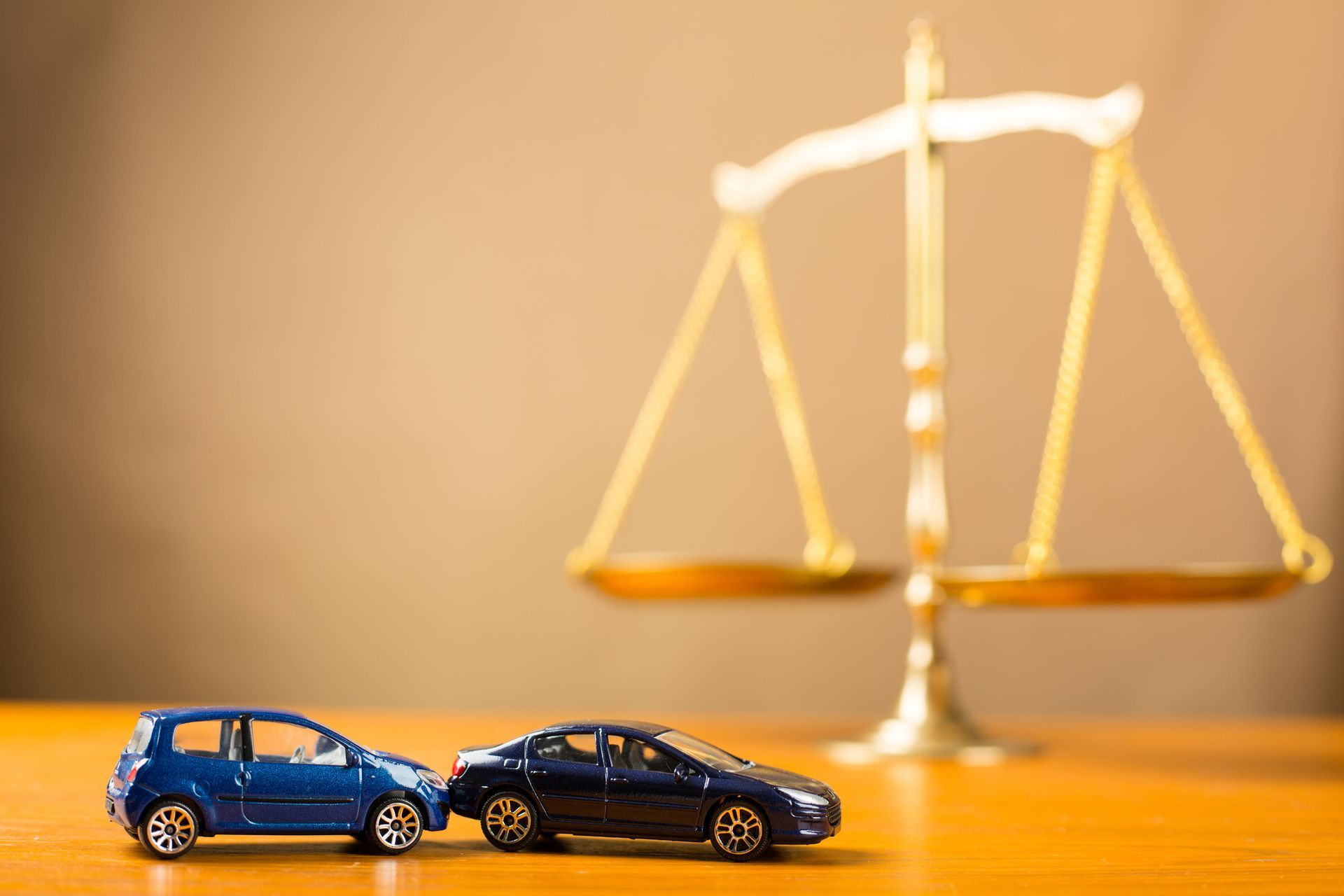Toy cars crash near justice scale symbolizing auto accident liability and legal compensation.