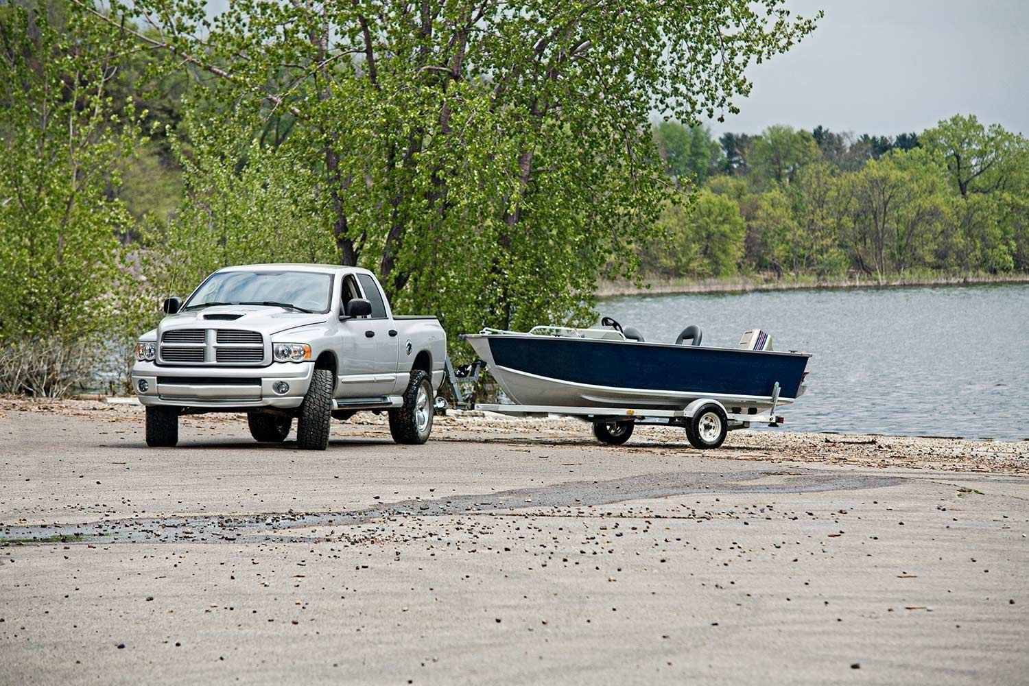A truck is towing a boat on a trailer — Garden City, ID — Barton’s Hitch & Trailer Service