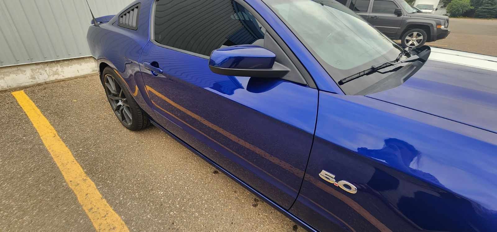 Blue Ford Mustang car parked in a parking lot.