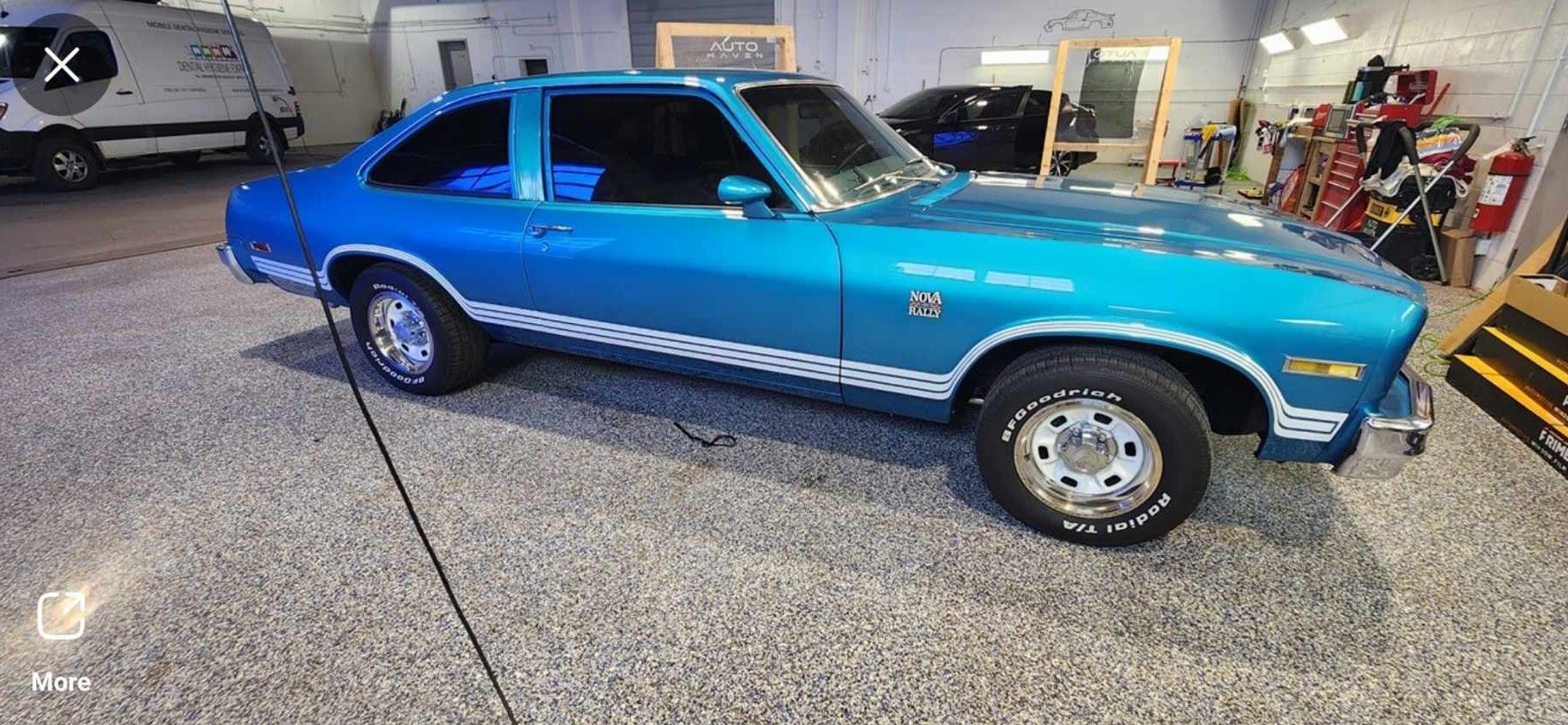 Blue classic car with white stripes parked inside a garage.