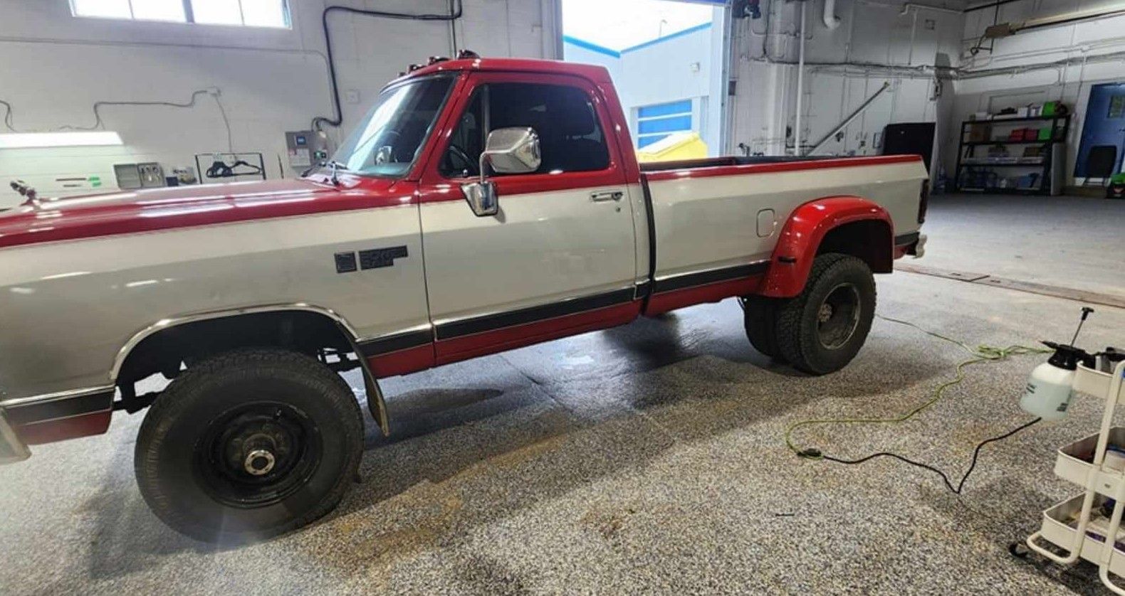 Red and silver vintage Dodge Ram dually pickup truck parked inside a garage.