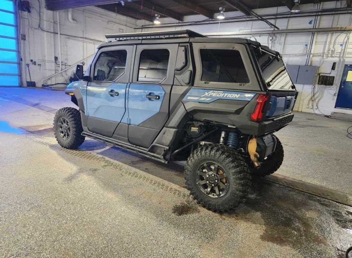 Blue and black custom off-road vehicle with large tires, in a garage.